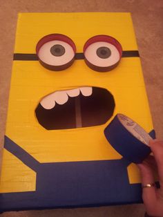 a cardboard cut out of a cartoon character with eyes and mouth, holding a tape