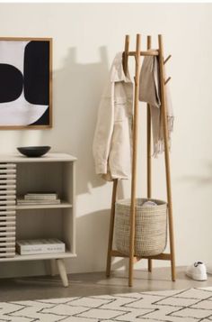 a coat rack with two coats hanging on it next to a rug and white shoes