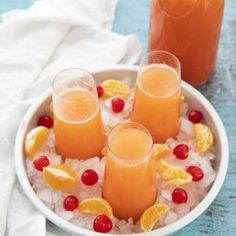 three glasses filled with orange juice on top of ice