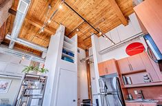 an open kitchen and living room with exposed wood ceiling, stainless steel appliances and cabinets