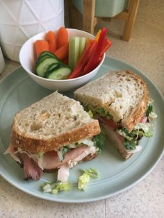 a sandwich cut in half sitting on top of a plate next to a bowl of vegetables