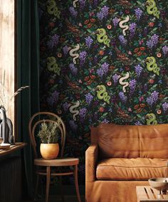 a brown leather couch sitting in front of a wallpaper covered in vines and flowers