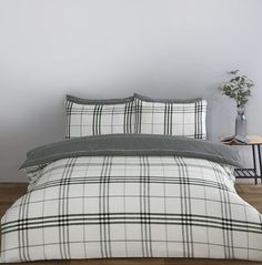 a white and black plaid comforter set on a wooden floor next to a table