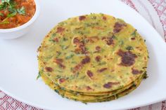 three tortillas on a white plate next to a bowl of salsa