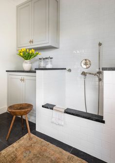 a bathroom with white cabinets and black counter tops is shown in this image, there are yellow flowers on the window sill