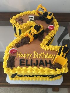 a birthday cake that is shaped like a number two with construction vehicles on it and the words happy birthday written in large letters