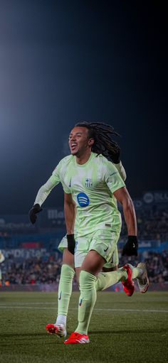 a soccer player is running on the field with his mouth open and one foot in the air