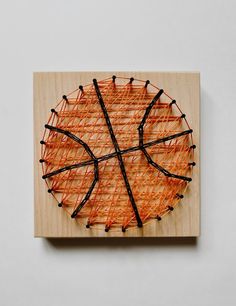 a piece of art made out of string and wood with a basketball ball on it