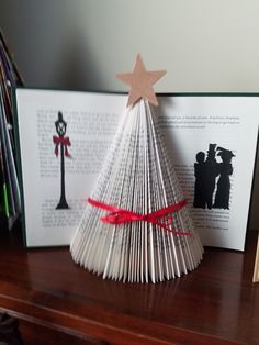 an origami christmas tree sitting on top of a table next to two books