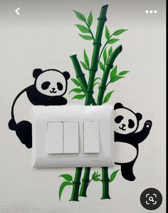 an electrical outlet with two pandas on it and bamboo in the wall behind them