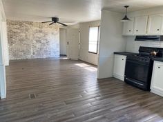 an empty kitchen with white cabinets and black appliances in the room that is painted white