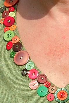 a woman wearing a green shirt with colorful buttons on the collar and necklace attached to her neck