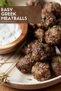 some meatballs are sitting on a plate with toothpicks and ranch dressing in the background