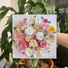 there is a painting made out of flowers in a potted planter on the table