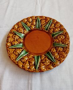 a brown and green plate sitting on top of a white table cloth