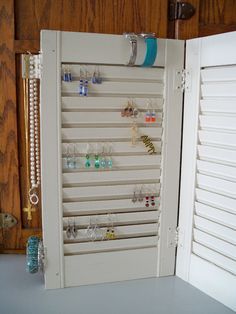 an open door to a jewelry cabinet with earrings hanging on the doors and earring hooks