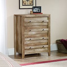 a wooden chest of drawers sitting on top of a hard wood floor next to a wall