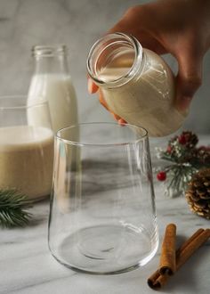 someone pouring milk into a glass with cinnamon sticks