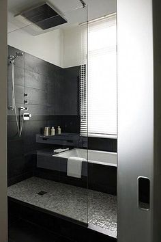 a black and white bathroom with a glass shower door that opens to the bathtub