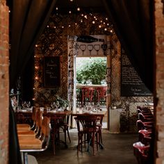 the inside of a restaurant with tables, chairs and lights hanging from the brick walls