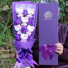 a man holding a purple box with hello kitty stuffed animals in it