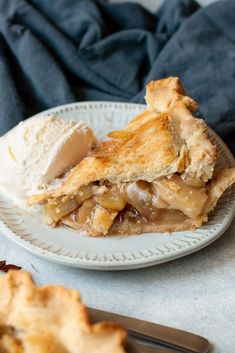 a slice of apple pie on a plate with ice cream and fork next to it