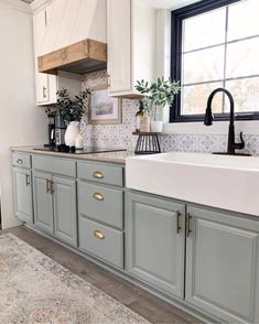 a kitchen with gray cabinets and white counter tops, gold pulls on the cabinet doors