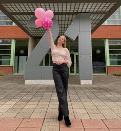 blonde girl holding pink balloons wearing silver crown, white polka dot shirt, leather pants and heels, standing in front of huge number 21, because it’s her 21st birthday