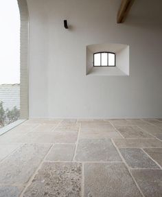 an empty room with stone flooring and a small window in the wall above it