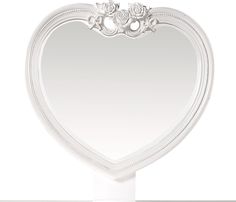 a white heart shaped mirror sitting on top of a table