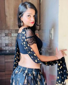 a woman in a black top and skirt standing next to a wall with polka dots on it