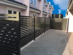 a black metal fence next to a pink house with white trimmings on it