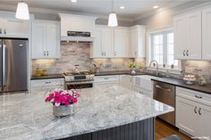 a large kitchen with white cabinets and granite counter tops, along with stainless steel appliances