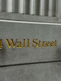 the four wall street sign is gold lettering on a gray building's front door