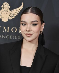 a woman in a black suit and earrings poses for the camera at an awards event