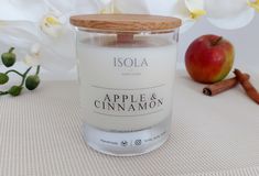 an apple and cinnamon candle next to some flowers