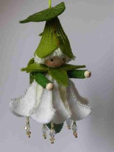 a small doll is dressed in white and green