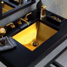 a bathroom sink with gold faucet and black countertop