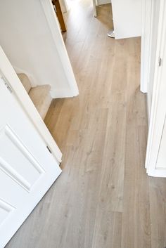 an empty hallway with white walls and wood flooring is seen from the top down