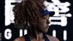 a woman with curly hair wearing a blue hat