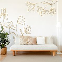 a white couch sitting next to a plant on top of a hard wood floor