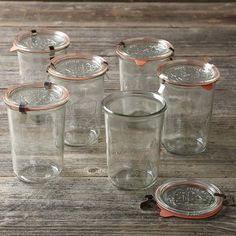 six glass jars with lids on a wooden table