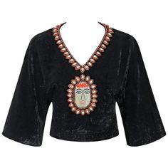 Extremely rare vintage Gucci c.1970's black crushed velvet cropped blouse. Bohemian beaded and embroidered detail at neckline and center front made up of blue and red rounded glass beads, faceted tear drop crystals with red and gold surrounding embroidery, and embroidered face detail. Short dolman sleeves. V-neckline. Banded waist. Crop style. Center back zipper with two hook and eye closures at hem. Fully lined in black signature "Gucci" lining. Please note sleeves have been altered to a shorte Clothing Blouses, Beaded Crop Top, Polyvore Items, Vintage Blouses, Fashion 70s, Boho Crop Tops, Embroidered Crop Tops, Embroidered Face, Crop Style