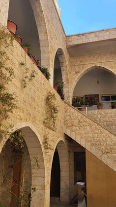 an arched building with potted plants on the balcony and stairs leading up to it