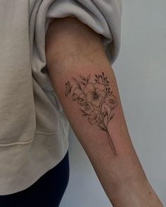 a woman's arm with flowers and leaves tattoo on the left side of her arm