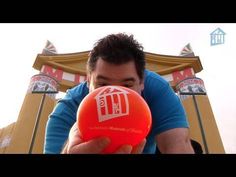 a man holding an orange frisbee in front of a building