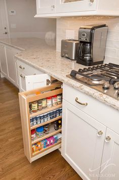 an open cabinet in the middle of a kitchen with white cabinets and wood flooring