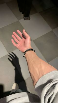 a person's hand reaching for something on the ground with their shadow in the background