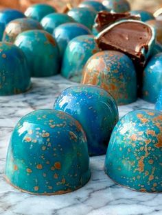 some blue and gold colored desserts sitting on a marble counter top with one chocolate bar in the middle