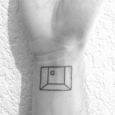 a black and white photo of a person's wrist with a small square tattoo on it